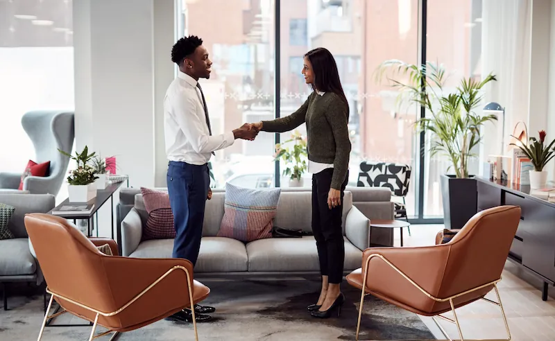 Une candidate et un recruteur se serrent la main dans un espace de rencontre